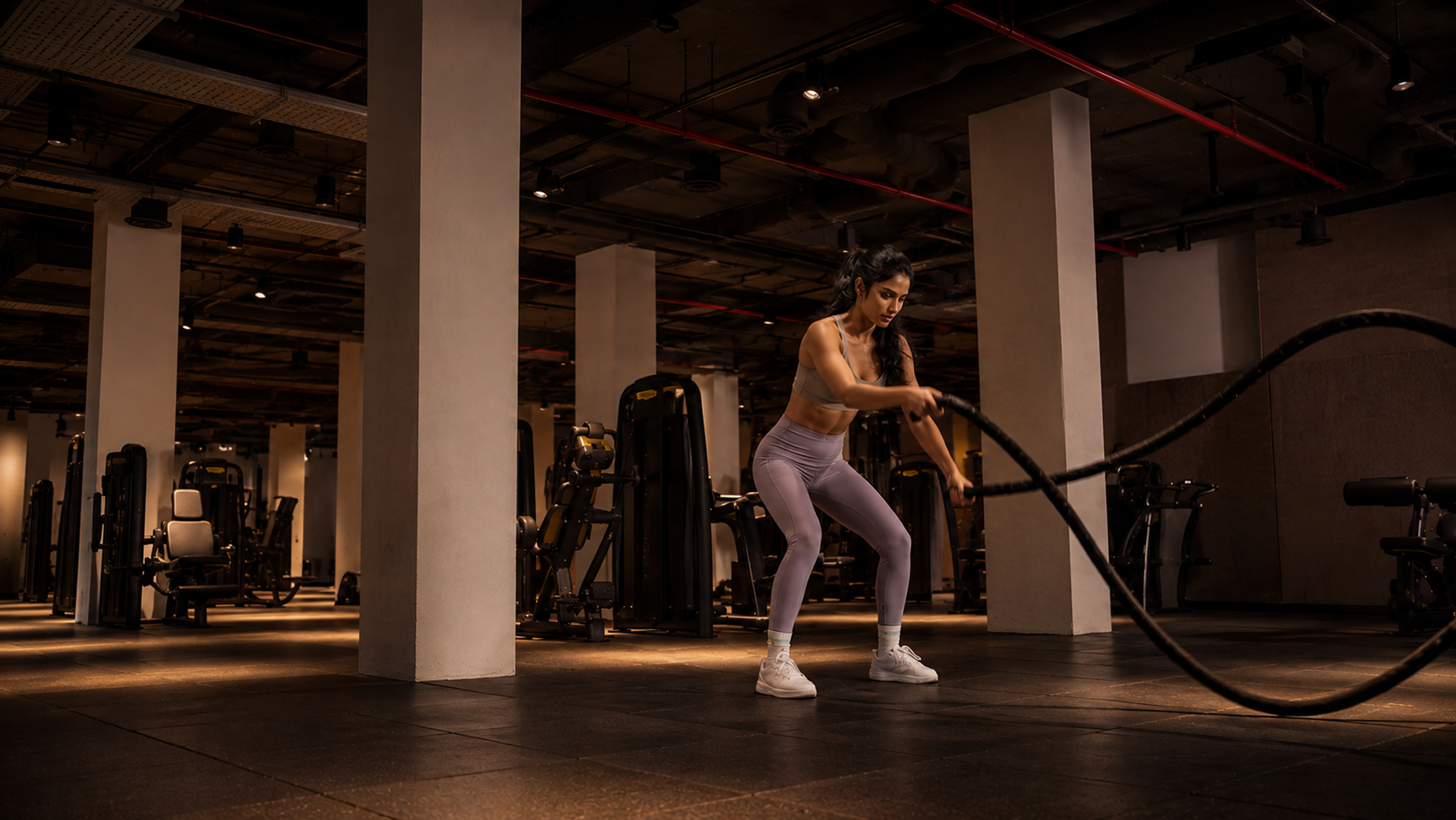 Woman training with battle ropes in a high-end fitness studio